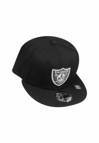 Schwarze Snapback-Cap aus Stoff mit flachem Schirm. Mit einem Raiders-Logo-Patch in Grau und Weiß auf der Vorderseite. Robuste Textur.