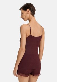 Burgunderfärgad ribbad linne med justerbara axelremmar, parat med matchande shorts som har en spetsdetalj. Mjuk tygkvalitet med åtsittande design.