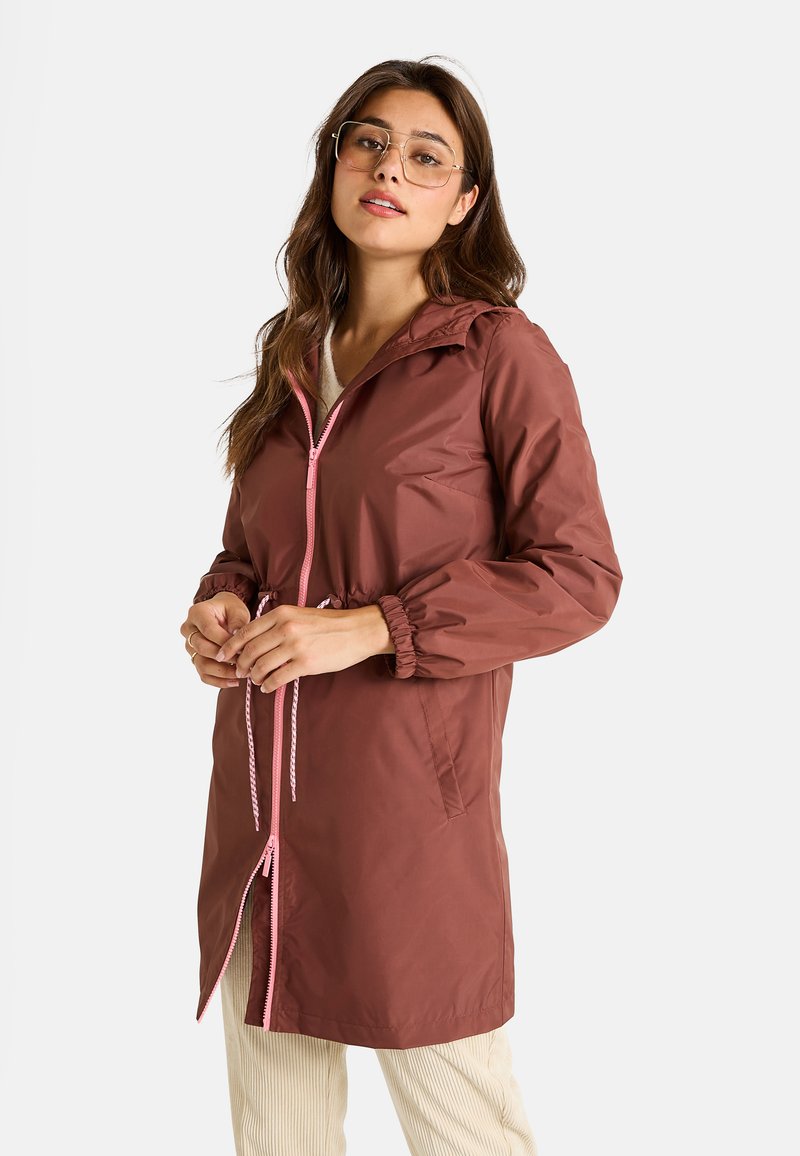 Parka marron résistant à l'eau avec capuche, fermeture éclair rose et détails de cordon de serrage, poches latérales et poignets élastiques. Matériau lisse et léger.