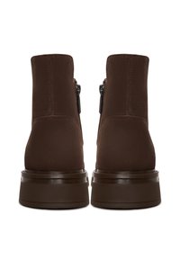 Botines de ante marrón con una superficie suave, cremalleras laterales y una suela de goma marrón gruesa, que presentan un diseño elegante y minimalista.