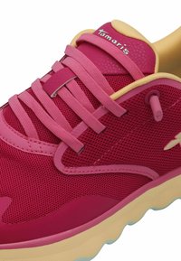 Sneaker rosa in rete con una parte superiore testurizzata, accenti gialli a contrasto e lacci piatti rosa. Presenta una suola spessa, di un giallo chiaro.