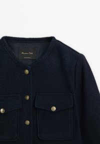Veste en laine bleu marine avec encolure ronde, deux poches à rabat frontales et des boutons décoratifs dorés au centre et sur les poches.