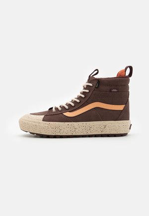 Zapatillas altas de ante marrón con suela salpicada de crema, acentos beige y pestaña en el talón naranja. Presenta cordones redondos y detalle del logo.