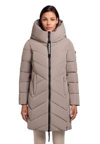 Pufferjakke i lys beige med et chevronmønster, høj krave og lynlås foran. Har sidelommer og et logo-tag.