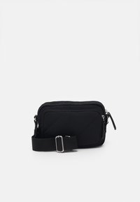 Sort nylon crossover taske med et quiltet mønster, justerbar strop og lynlåslommer til sikker opbevaring.