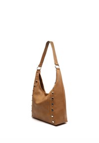 Sac à bandoulière en cuir fauve avec une large sangle et des clous métalliques argentés le long des côtés, présenté sur un fond blanc.