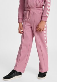 Roze joggingbroek met een getextureerde afwerking, voorzien van witte chevronstrepen aan de zijkanten en een elastische tailleband voor een verstelbare pasvorm.