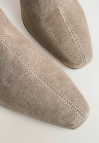 Gray suede ankle boots with a pointed toe, featuring visible stitching and a smooth texture. The design is minimalist and sleek.