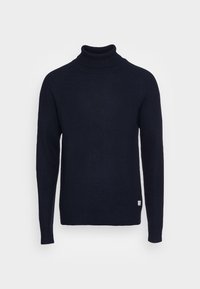 Mörk marinblå ribbad stickad polotröja med långa ärmar och en liten vit märke nära fållen på en neutral bakgrund.