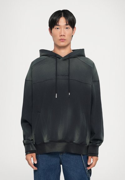 Zwarte en donkergroene gradient hoodie met een trekkoord capuchon, een voork pocket en een reliëflogo. Katoenen stof, ontspannen pasvorm, lange mouwen.