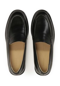Black leather loafers with a smooth finish, rounded toe, and low profile. Inside features a beige lining with branding. Soft sole.