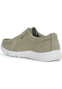 Chaussure en toile gris clair avec une surface texturée, semelle en caoutchouc blanche et petits œillets pour les lacets. Dos lisse avec bords arrondis.