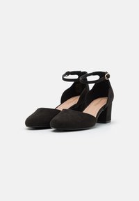 Black suede high-heeled shoes with a pointed toe and ankle strap, featuring a sturdy block heel and smooth interior.