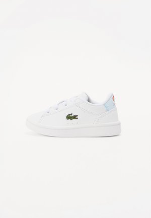 Sneaker bianca in pelle con suola piatta, punta rotonda e logo di coccodrillo ricamato verde. Presenta lacci bianchi e un accento di tallone blu chiaro.