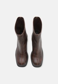 Braune Leder-Ankle-Boots mit glatter Textur, quadratischer Zehenform und minimalen Nähten. Schwarze Gummisohle für besseren Halt.