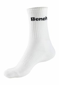 White cotton sock with ribbed texture, reinforced toe, and heel. Features the brand name "Bench" in black on the top band.