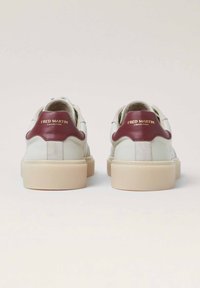 Sneakers bianchi in pelle con un accento borgogna sulla linguetta e dettagli dorati. Suola spessa color crema, con dettagli in suede sul retro.
