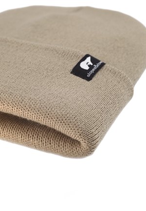 Beige knit beanie with a folded cuff, featuring a black label with a white stylized animal logo. Soft texture and simple design.