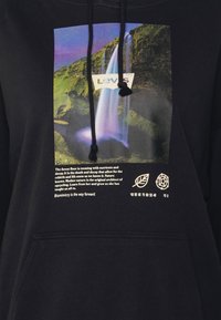 Felpa nera con cappuccio caratterizzata da una grafica di una cascata colorata e dal logo Levi's. Tasca frontale, testo sottostante con simboli di foglia e cerchio.