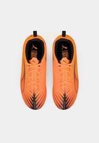 Πορτοκαλί αθλητικά παπούτσια με υφασμάτινο σχέδιο, διαθέτοντας μαύρες λεπτομέρειες, στρογγυλή μύτη και μαύρη επένδυση εσωτερικά. Οι κορδόνια είναι φωτεινά πορτοκαλί.