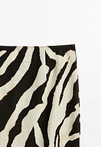 Gonna a stampa zebra con audaci strisce nere e crema, realizzata in un tessuto testurizzato con cuciture visibili lungo la vita.