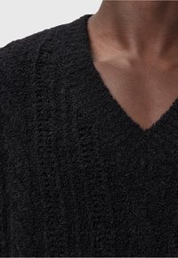 Czarny, teksturowany sweter typu pulower z dekoltem w serek, wykonany z miękkiej, pętlowej tkaniny i delikatnymi pionowymi wzorami.