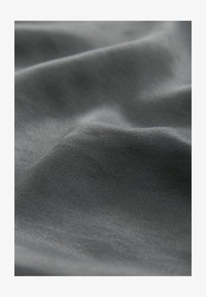 Tuva tuvu tumši pelēka auduma struktūra ar mīkstām locījumiem un gludu, cieši austu virsmu.