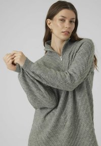 Maglione grigio chiaro, lavorato a maglia, con colletto alto e chiusura a mezza zip. Presenta un motivo diagonale testurizzato e polsini a coste.