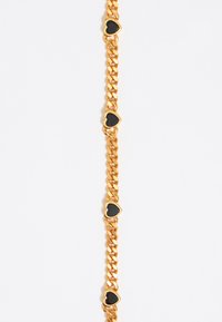 Pulsera de cadena de oro con acentos alternos de corazones negros. Los eslabones suaves y brillantes crean un diseño audaz.