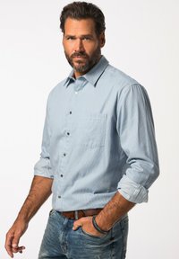 Hellblau gestreiftes Hemd mit Knöpfen, einer Brusttasche, hochgekrempelten Ärmeln und dunklen Knöpfen, kombiniert mit verwaschenen blauen Jeans und einem braunen Gürtel.
