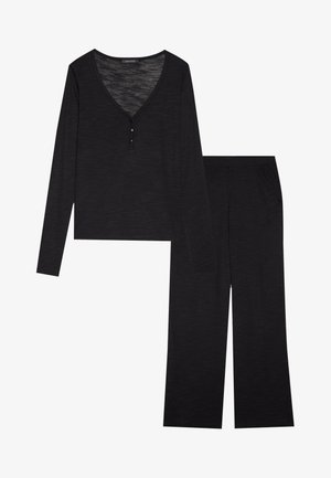 Juodas laisvalaikio kostiumas, kuriame yra ilgos rankovės V formos iškirptės marškiniai su mygtuko detale ir plačios kojos kelnės. Audinys turi subtilų tekstūrą.