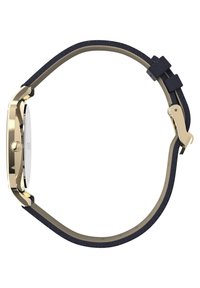 Reloj de metal en tono dorado con esfera redonda, correa de tela azul marino y herrajes dorados. Presenta un diseño minimalista y una textura suave.