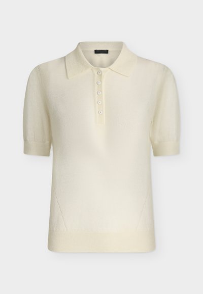 Polo en tricot crème à manches courtes avec col et cinq boutons sur le devant, ourlet et poignets côtelés, présenté sur fond blanc.