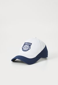 Cappellino da baseball bianco e blu navy con logo ricamato che presenta un design circolare e la scritta "FC COPENHAGEN". Materiale in cotone, forma strutturata.