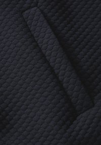 Tessuto testurizzato blu navy con un motivo trapuntato, caratterizzato da un bordo piegato per aggiungere profondità e dimensione. Texture morbida e intrecciata.