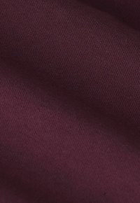 Tissu en coton bordeaux avec une surface lisse et légèrement texturée ; présente une couleur uniforme et un motif de tricot visible.