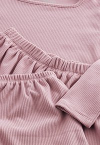 Tessuto a righe rosa con una superficie texture; presenta un orlo arricciato e aree arricciate elastiche. Mostra una finitura liscia e morbida.