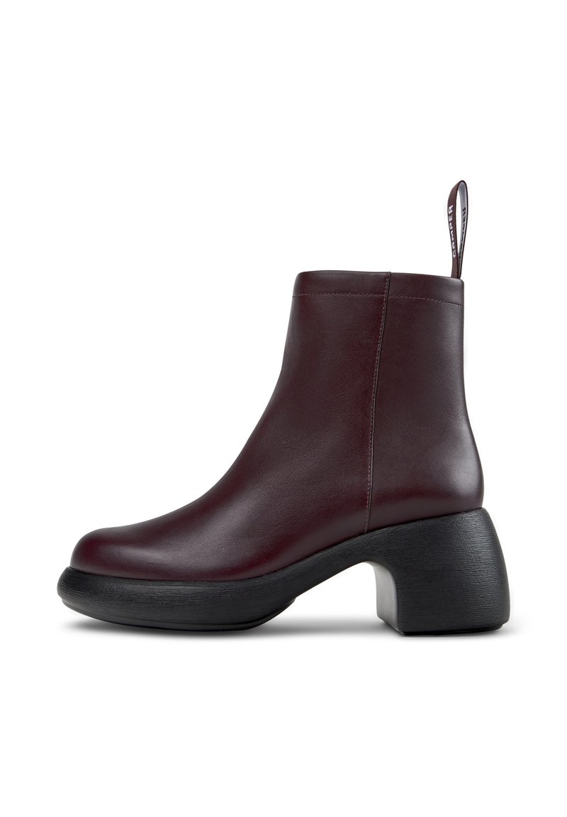 Stivaletti alla caviglia in pelle bordeaux con finitura liscia, punta rotonda e tacco spesso nero. Dotati di un pratico strap sul retro per indossarli facilmente.