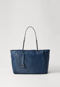 Granatowa torba na ramię z łańcuchowymi ramiączkami, zawieszoną okrągłą zawieszką z logo oraz subtelnym napisem z nazwą marki z przodu.