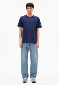 Marineblauwe katoenen t-shirt met een ronde hals, gecombineerd met losse, lichtblauwe denim jeans. Casual schoeisel maakt de outfit compleet.