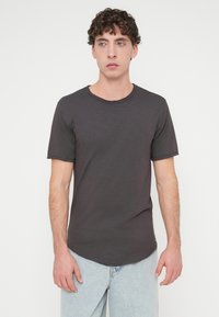 Σκούρο γκρι μπλουζάκι με κοντά μανίκια, στρογγυλή λαιμόκοψη και χαλαρή εφαρμογή. Το ύφασμα έχει διακριτική υφή και φινίρισμα με ατελείωτο τελείωμα.