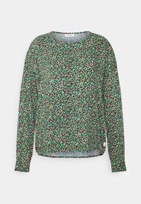 Maglietta a maniche lunghe con un motivo floreale verde, marrone e bianco. Presenta un colletto rotondo e una vestibilità rilassata con spacchi laterali all'orlo.