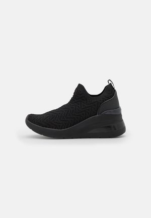 Czarny sneaker typu slip-on z teksturowaną dzianinową cholewką, grubą podeszwą, pętelką na pięcie i geometrycznym wzorem na tkaninie.