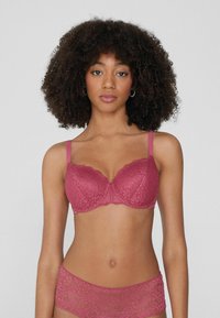 Koronkowy stanik w ciemnoróżowym kolorze z wsparciem w postaci fiszbin, regulowanymi ramiączkami, kwiatowym wzorem i falbaniastymi krawędziami. W komplecie z pasującymi koronkowymi majtkami.