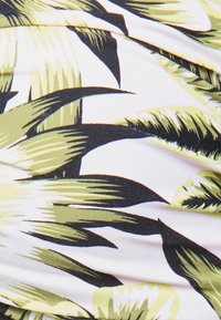 Tecido com estampa de folha tropical em verde e preto sobre um fundo branco, feito de um material fluido e texturizado.