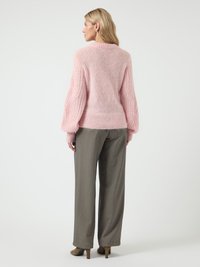 Sweater rosa claro de malha com um corte amplo, apresentando mangas texturizadas e uma bainha canelada; combinado com calças cinza de perna larga e saltos castanhos.