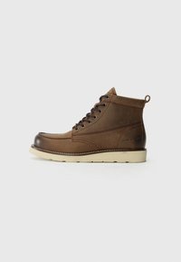 Botas altas de cuero marrón con puntera redondeada, acentos en marrón oscuro, suela resistente y un lazo en la parte trasera.
