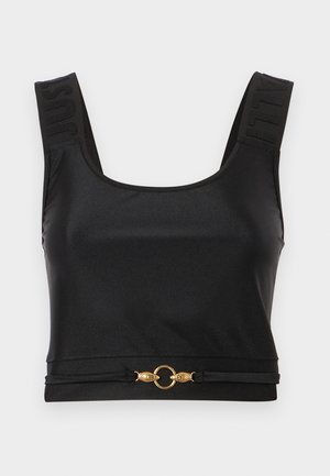 Svart crop top laget av glatt stoff. Har brede stropper med preget tekst og en gullsirkel aksent i kanten. Enkel, stilren design.