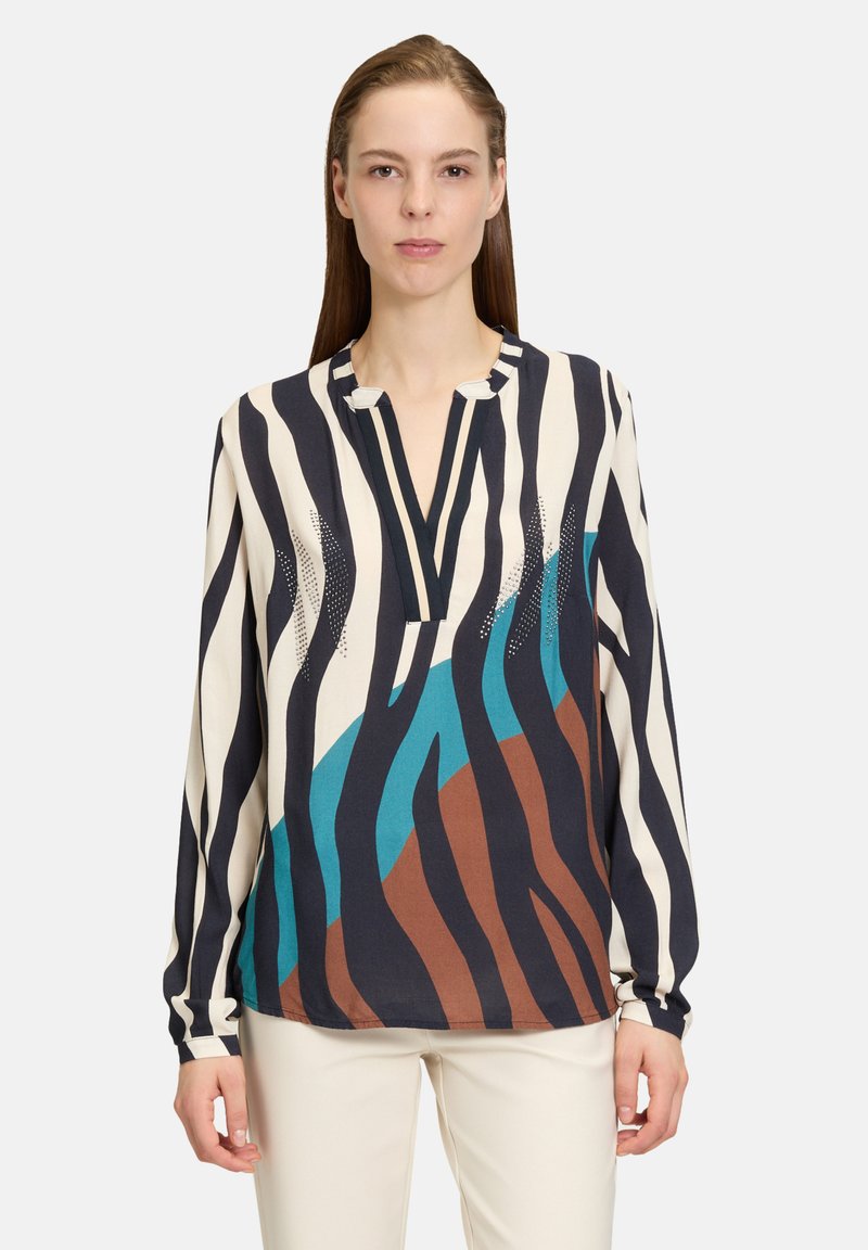 Blouse à manches longues en crème avec des rayures noires et bleues, dotée d'une patte de boutonnage partielle et d'une coupe décontractée. Impressions texturées en marron.