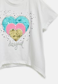 Weißes T-Shirt mit kurzen Ärmeln, das drei übereinanderliegende Herzen aus Pailletten in Blau, Pink und Gold zeigt, mit dem silbernen Text "desigual" darunter.